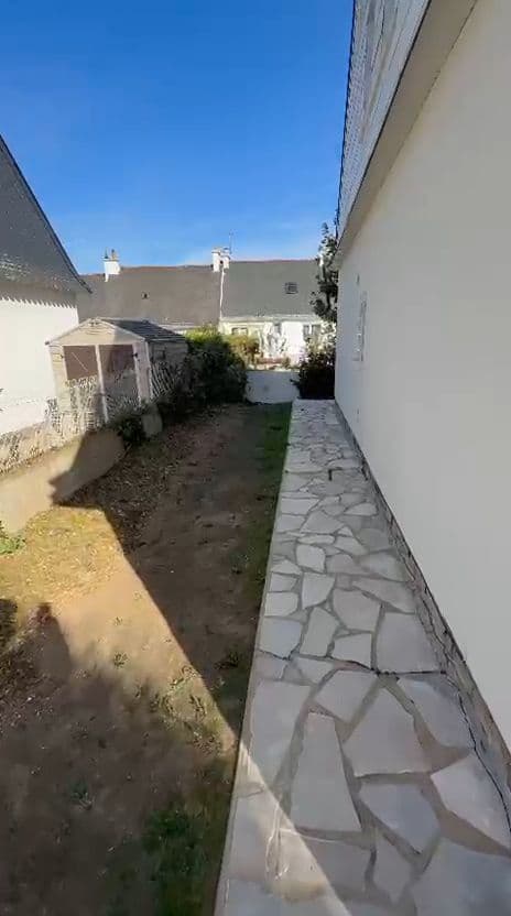 Passage dallé le long d'une maison, terre nettoyée et clôture dégagée jusqu'au cabanon