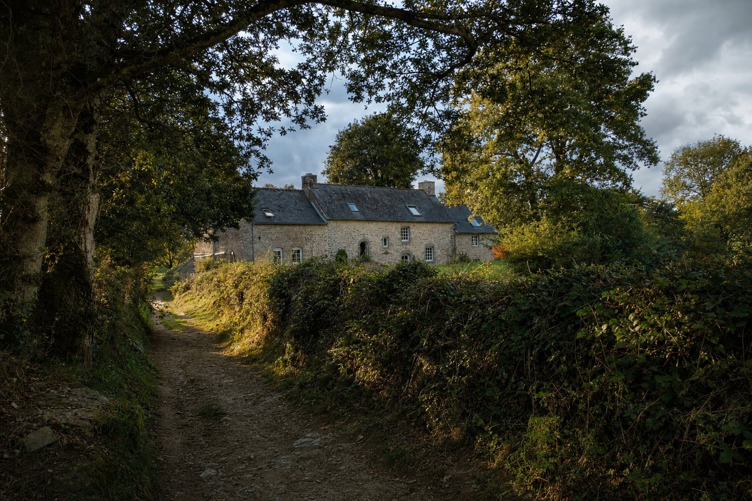 Une longère bretonne à Guidel entourée de grands chênes et d'une haie champêtre, chemin creux
